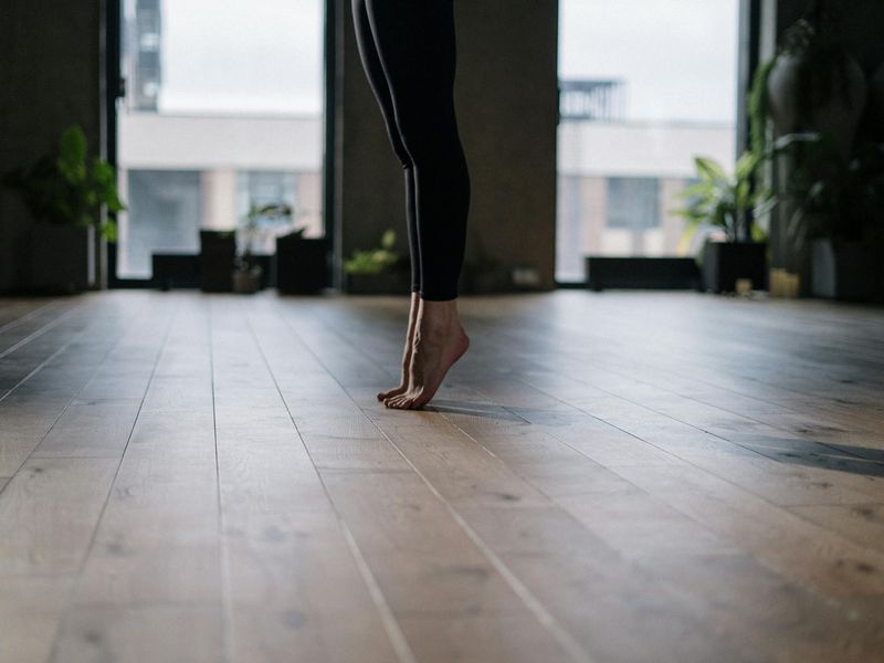 Person practicing yoga in a bright minimalistic studio with wooden floors